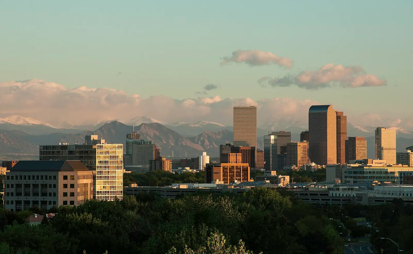 Downtown Denver skyline at golden hour with the snow-capped Rocky Mountains rising behind the skyscrapers, Colorado