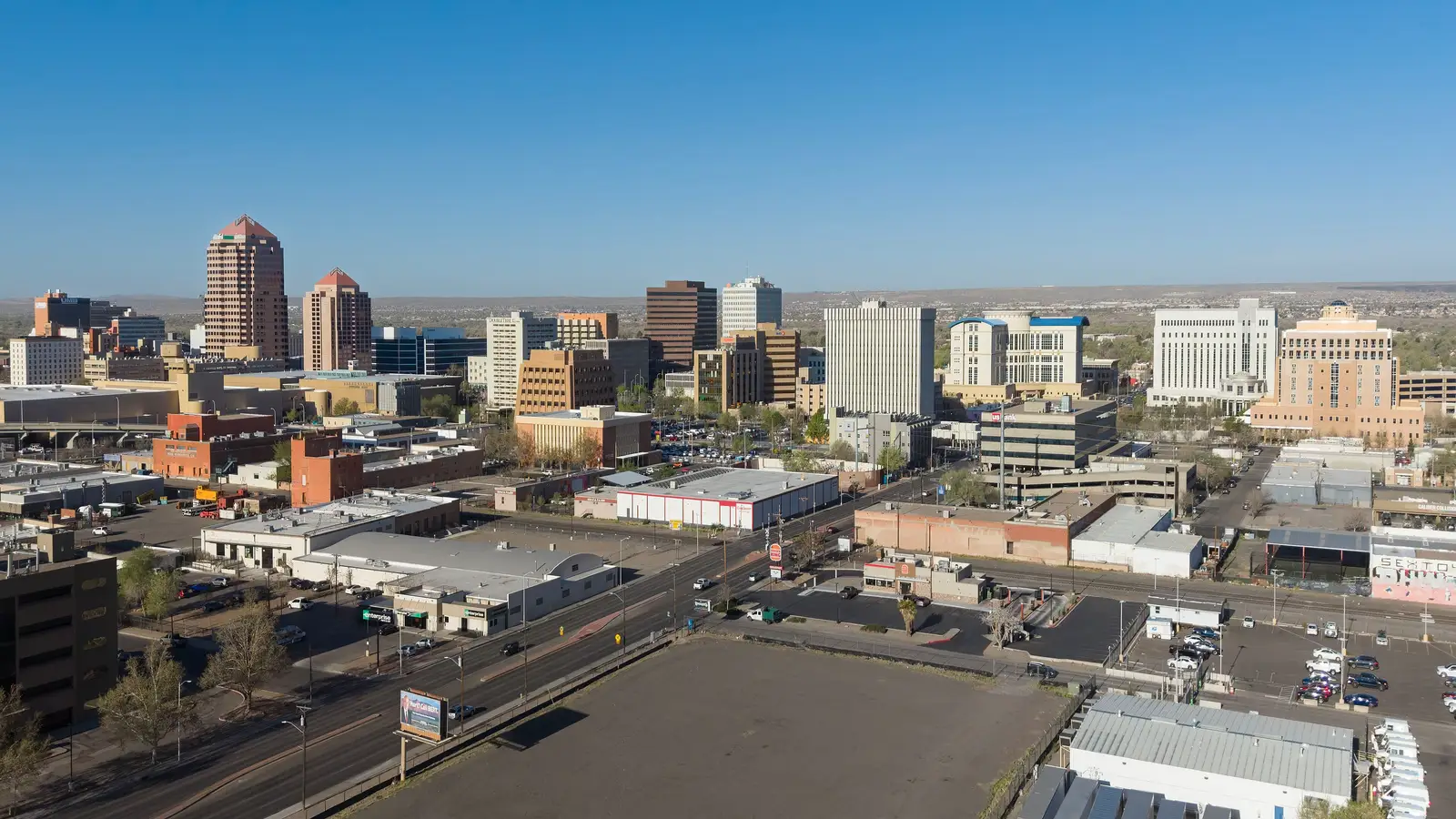 Elevated view of the downtown Albuquerque, New Mexico skyline with mid-rise office towers against a clear sky