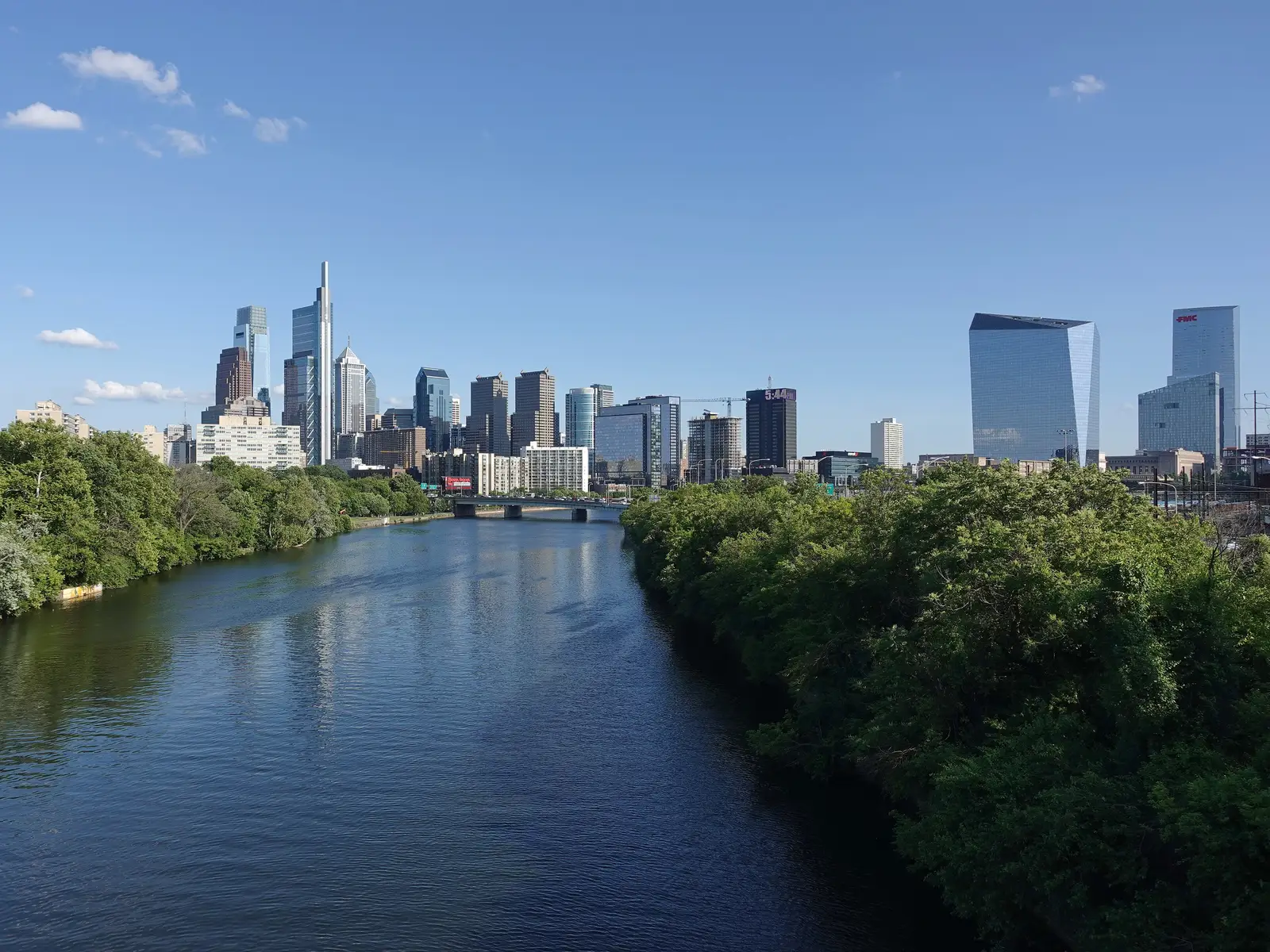 Philadelphia skyline reflected in the Schuylkill River under a blue sky with scattered clouds, Pennsylvania