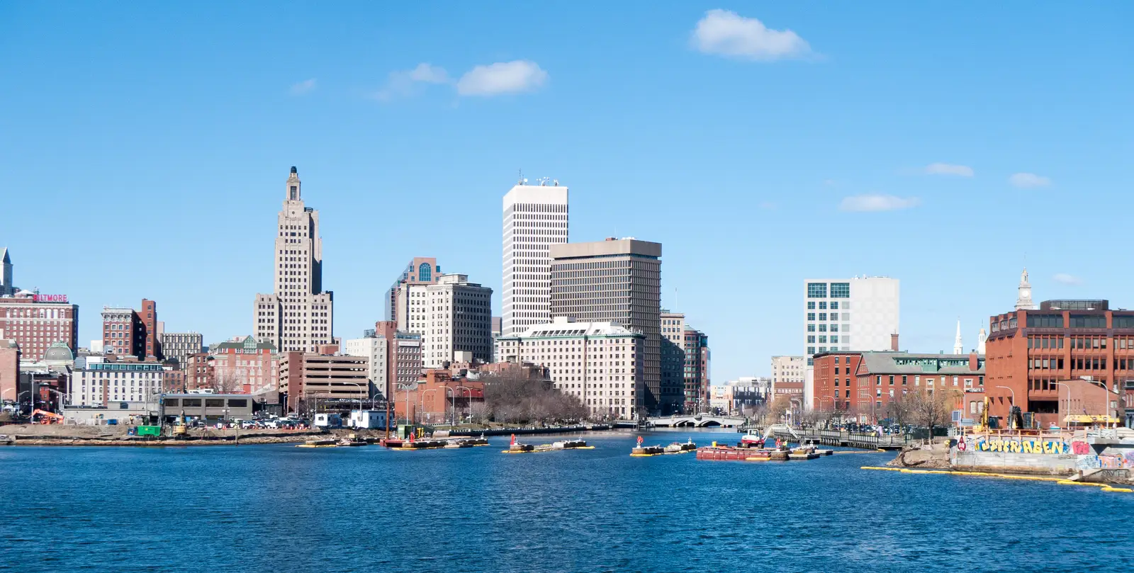 Downtown Providence, Rhode Island skyline viewed across the river, with modern high-rises and historic buildings under a daylight sky