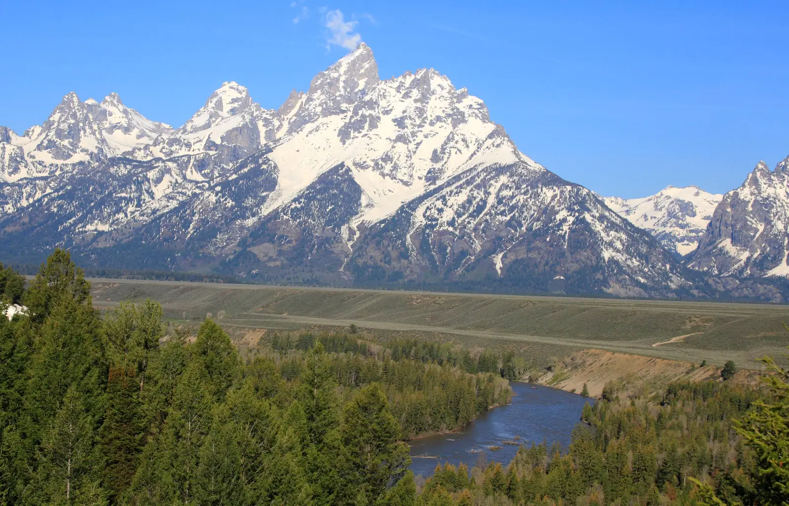 The jagged, snow-capped peak of Grand Teton rising above the Snake River valley, viewed from the Snake River Overlook, Wyoming