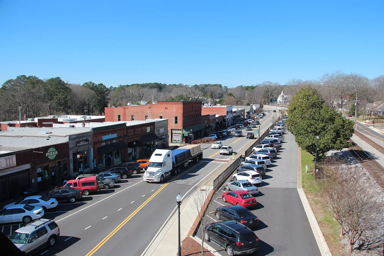 Elevated view down historic Main Street in downtown Acworth, Georgia, with brick storefronts and a church steeple beyond