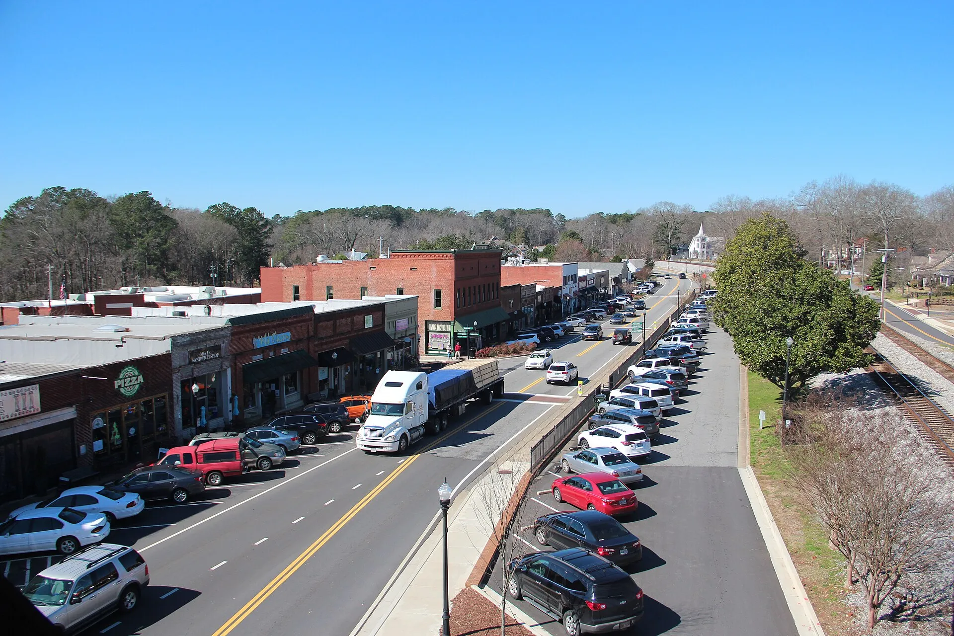 Elevated view down historic Main Street in downtown Acworth, Georgia, with brick storefronts and a church steeple beyond