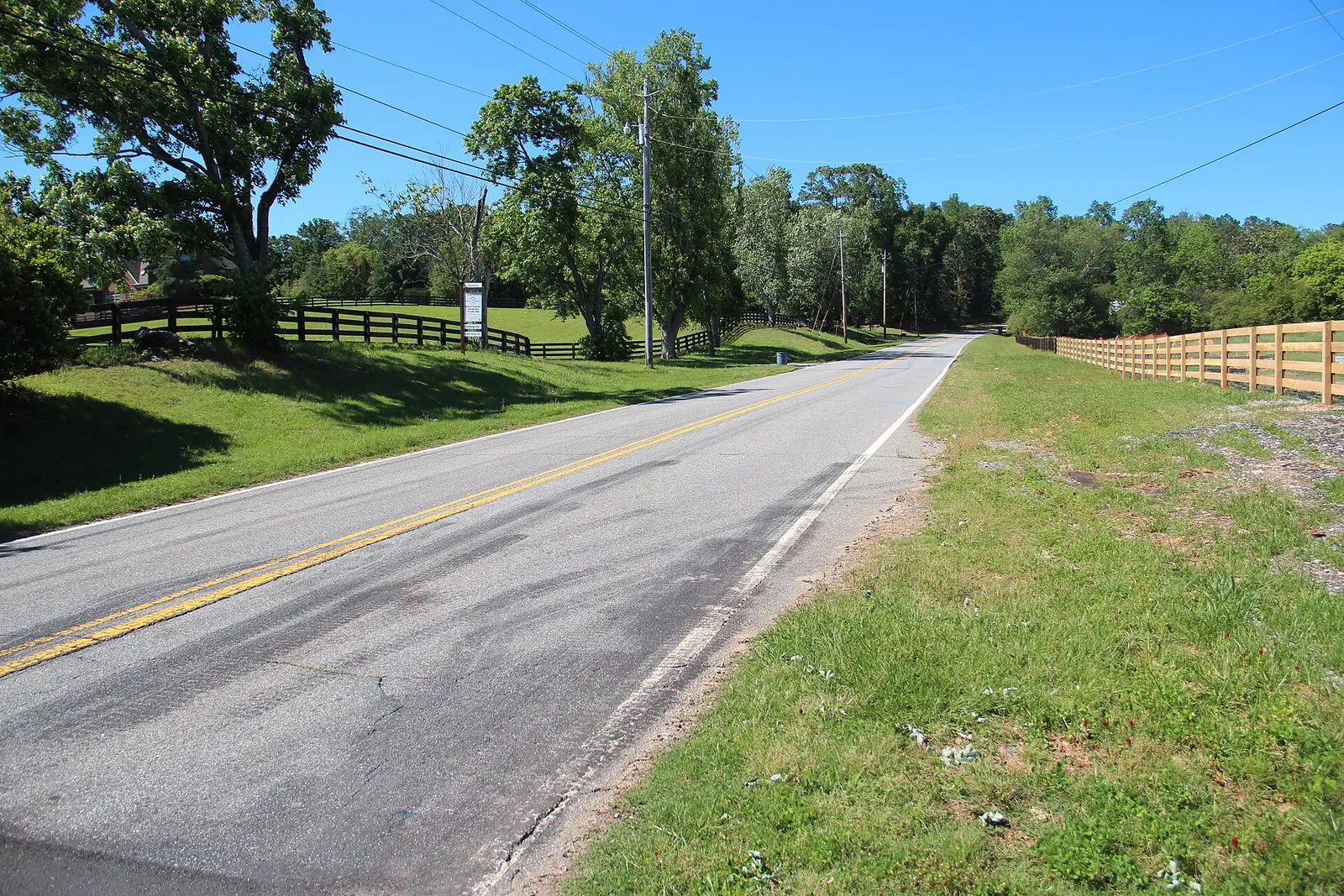 Wooden four-board horse-farm fences lining Freemanville Road through green pastures in Milton, Georgia