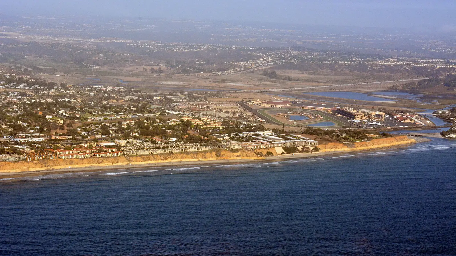 Aerial view of the Del Mar, California coastline, with beach, sea-cliff bluffs, and homes above the Pacific
